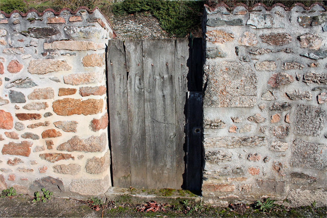 Weathered wooden gate set into a stone garden wall